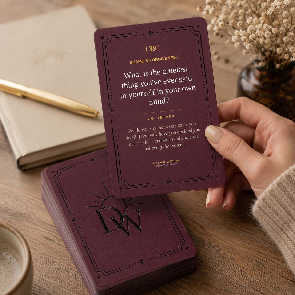 A hand lifting a Shadow Deck prompt card from the deck, beside a journal and coffee